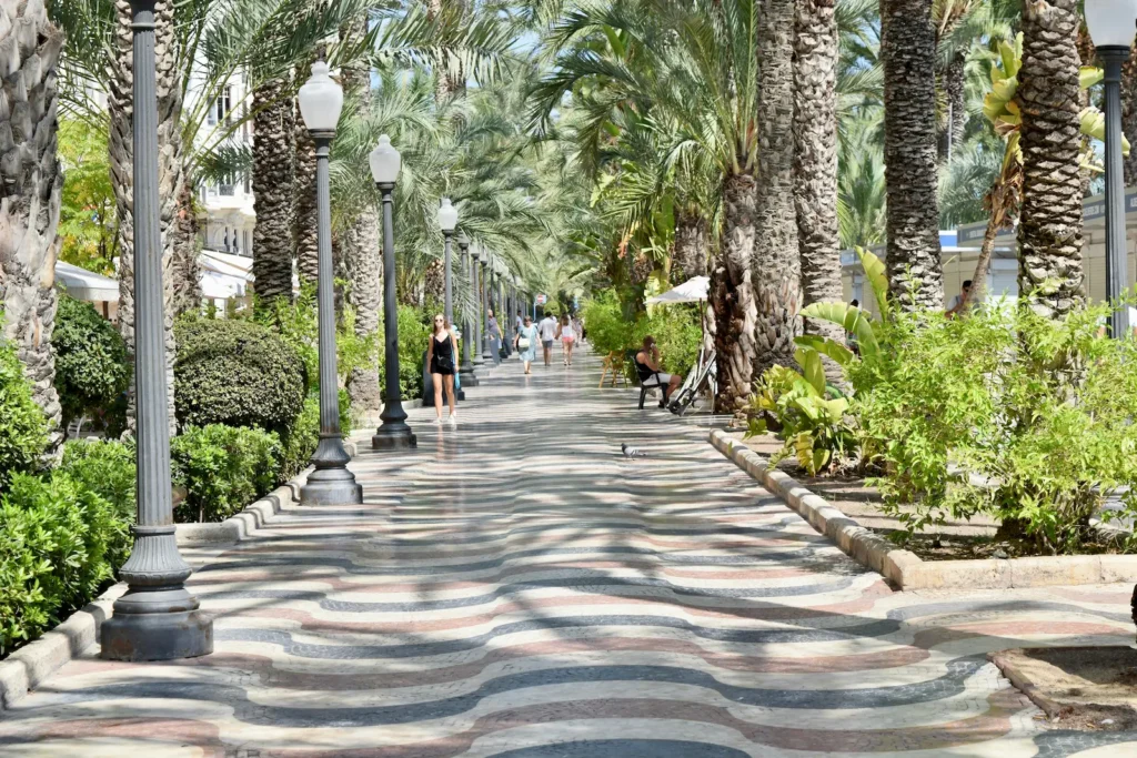 People walking along the palm-lined Explanada de España promenade in Alicante on a sunny day