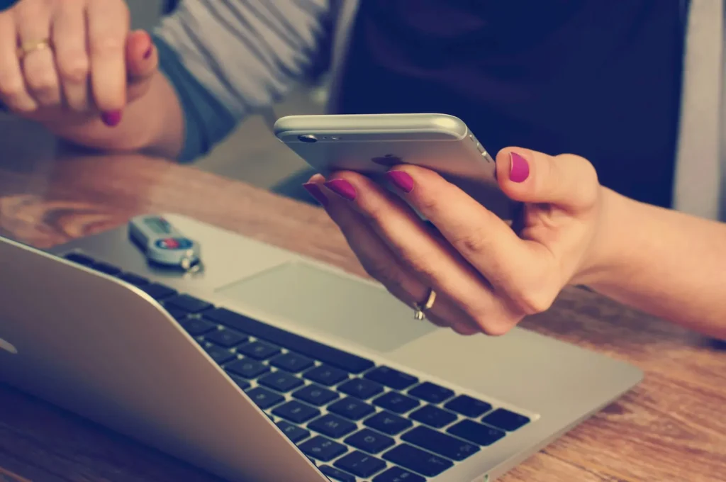 Person using phone and laptop in a cafe