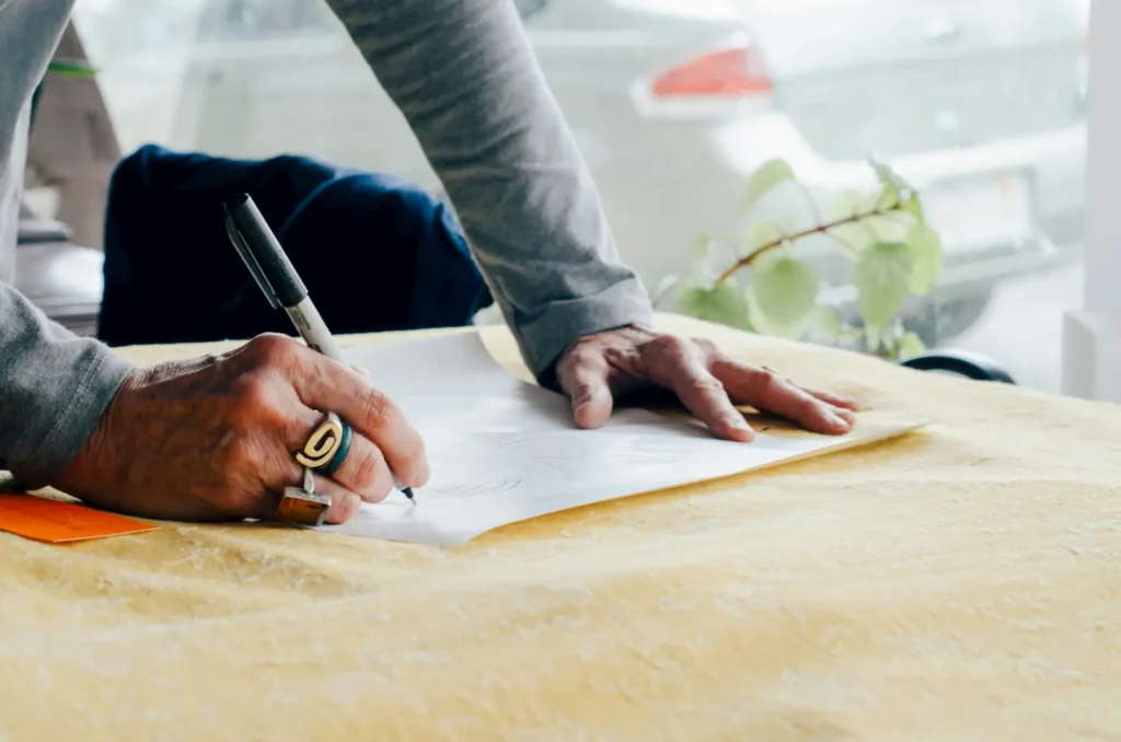 Person signing a document with a pen