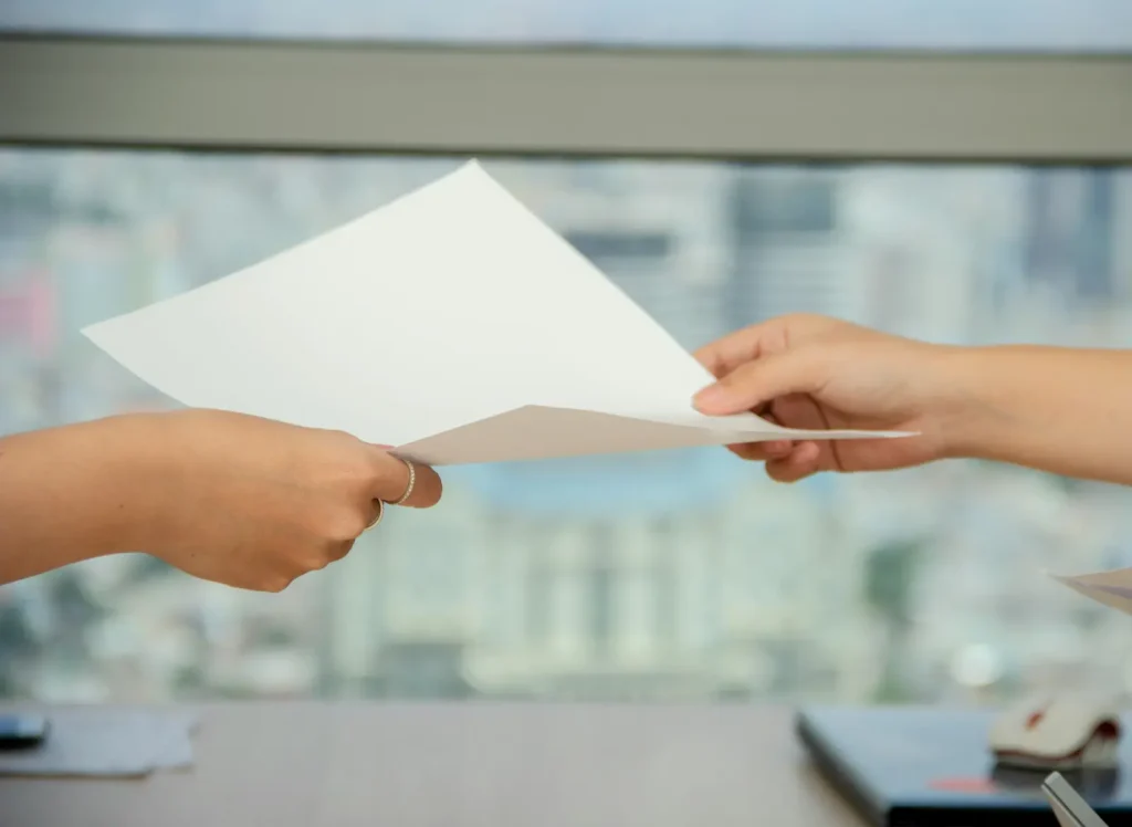 Two hands exchanging a document at a desk