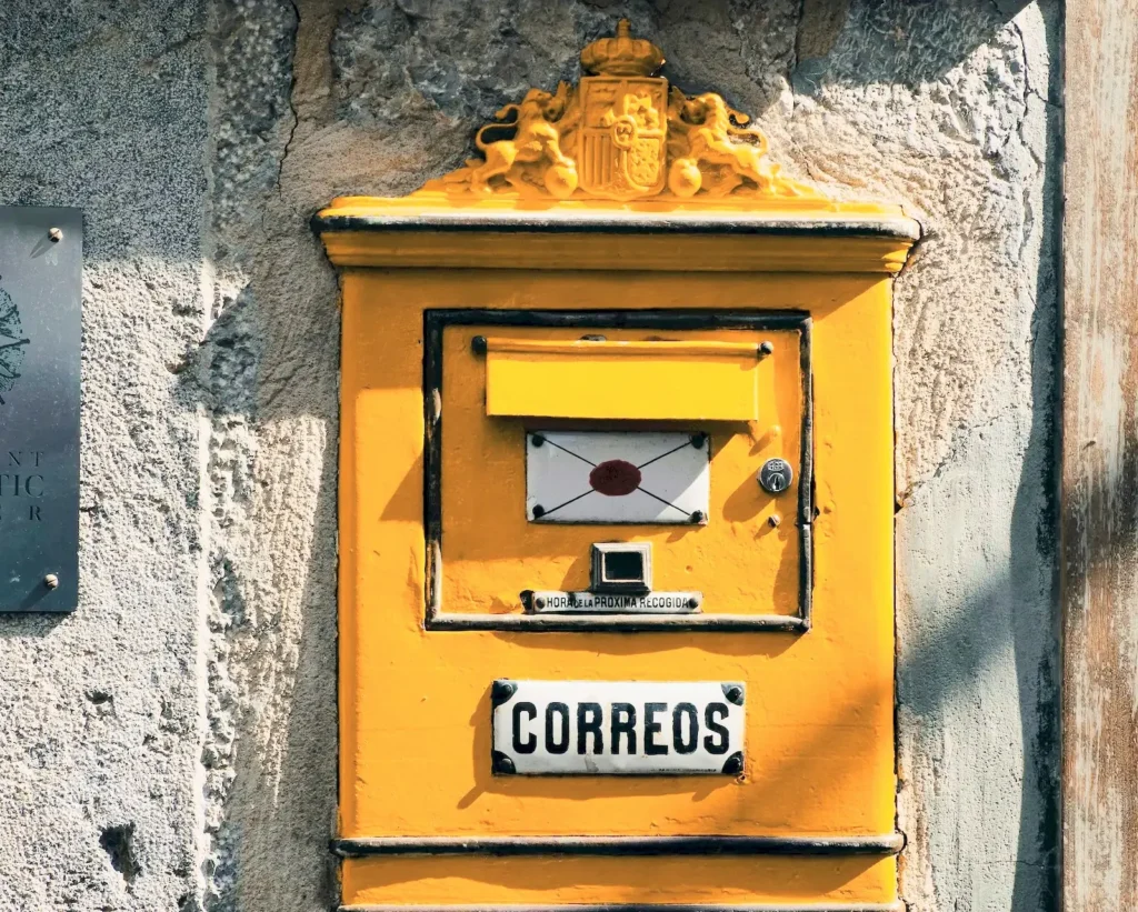 Yellow Spanish Correos postbox on a stone wall — official post in Spain